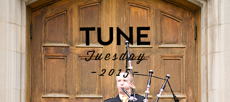 Bagpiper standing in front of wooden doors